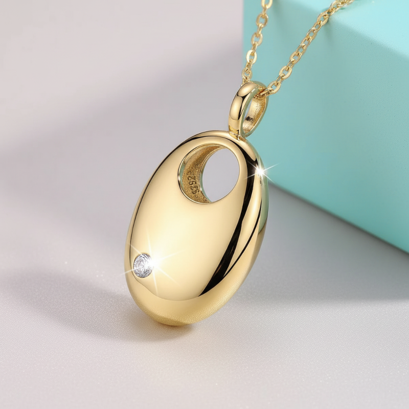 Gold pendant necklace with a diamond on a light gray background