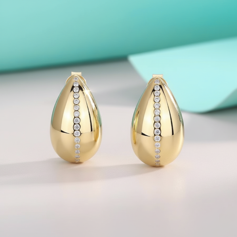 Gold teardrop earrings with embedded stones on a light background