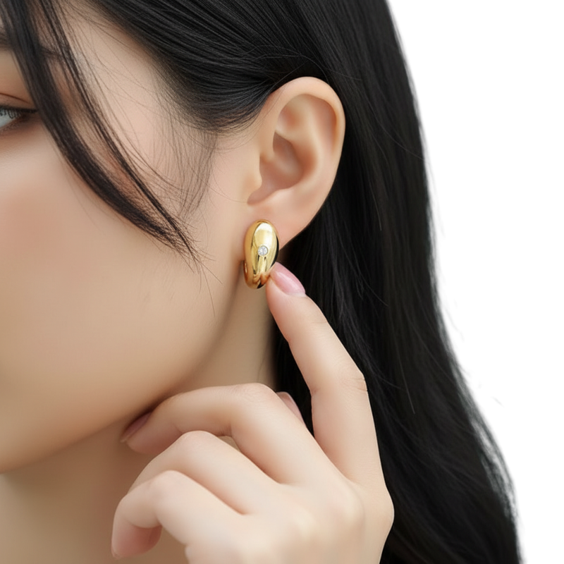 Close-up of a person wearing a gold earring with a neutral background