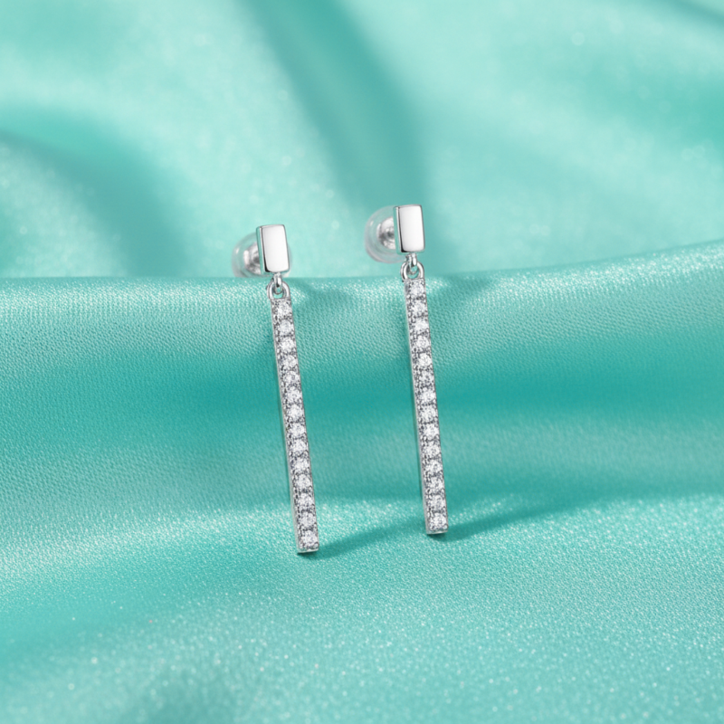 Silver earrings with clear stones on a teal fabric background