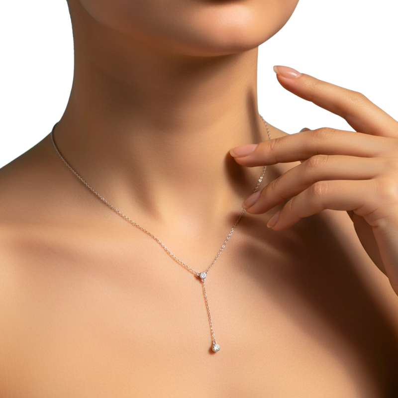 Necklace with small pendants on a model's neck with a hand touching it, on a white background