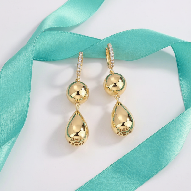 Gold teardrop earrings on a light blue ribbon