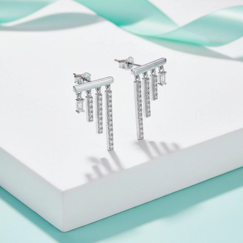 Silver earrings with dangling crystals on a light blue and white background