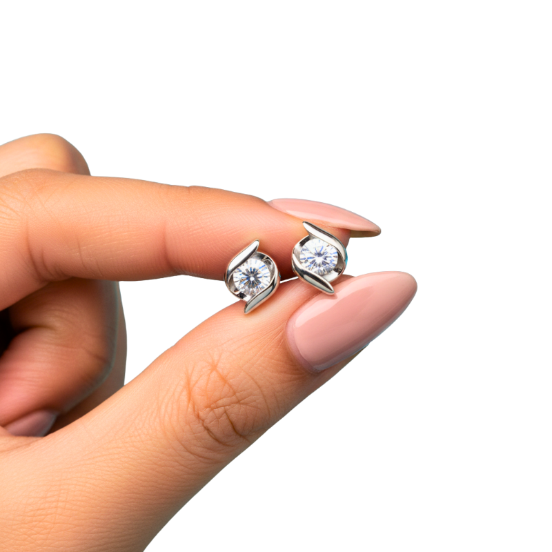 Diamond stud earrings held between fingers on a white background