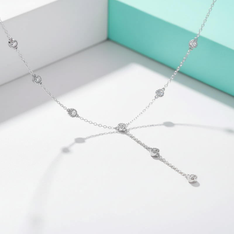 Silver necklace with floral designs on a light gray surface