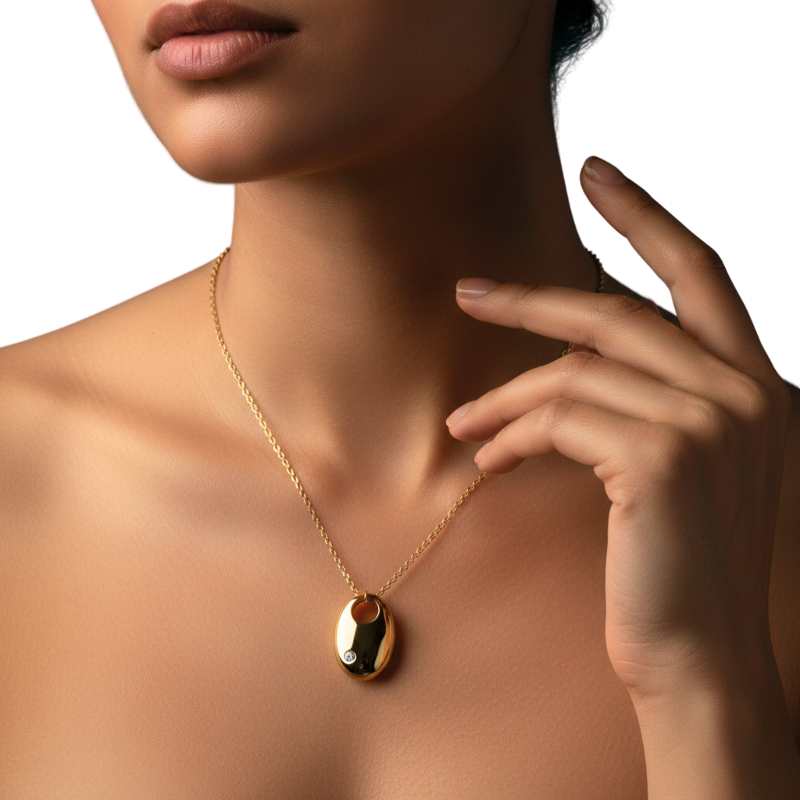 Gold necklace with a pendant worn by a person, with a hand touching the neck.