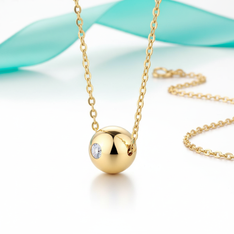 Gold necklace with a round pendant featuring a clear gemstone on a light blue background
