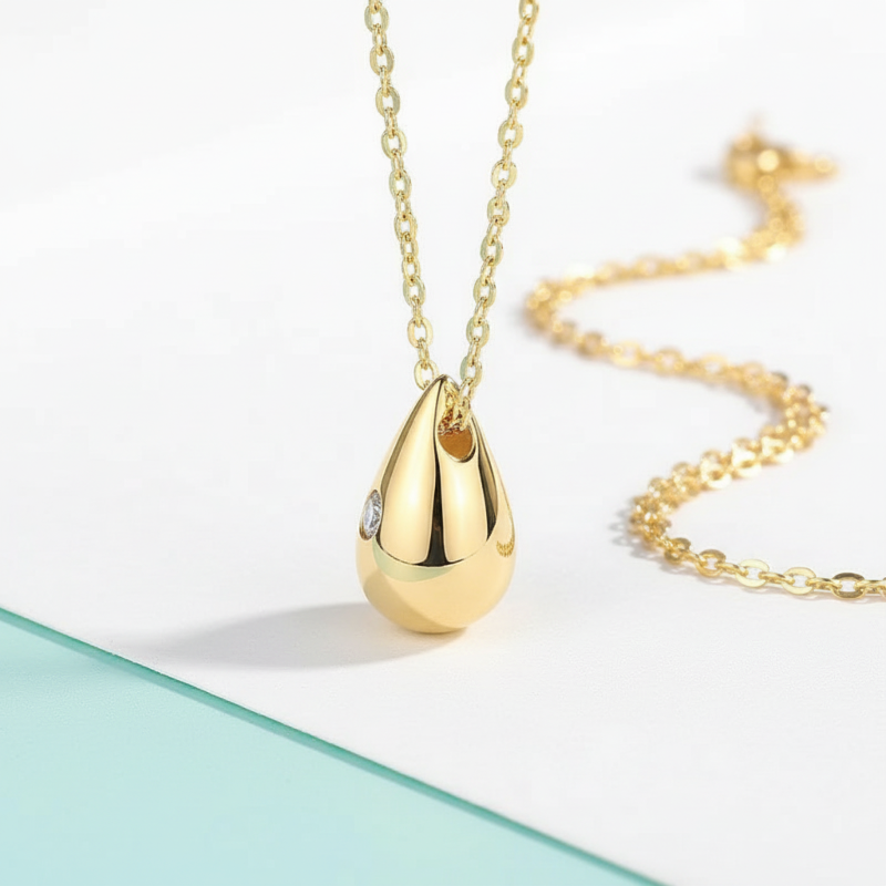 Gold teardrop pendant necklace on a light background