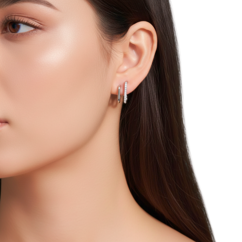Close-up of a woman wearing silver hoop earrings with a neutral background