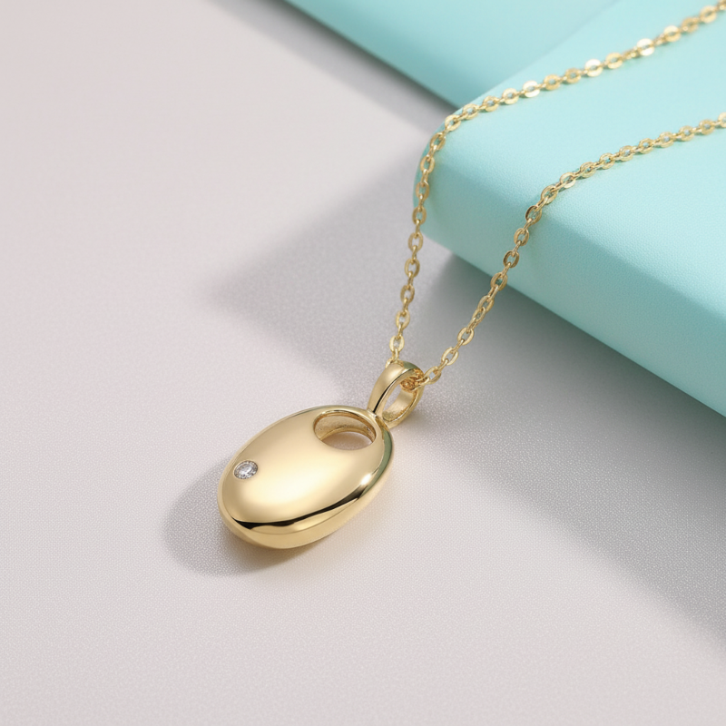 Gold pendant necklace on a light gray surface with a turquoise box in the background
