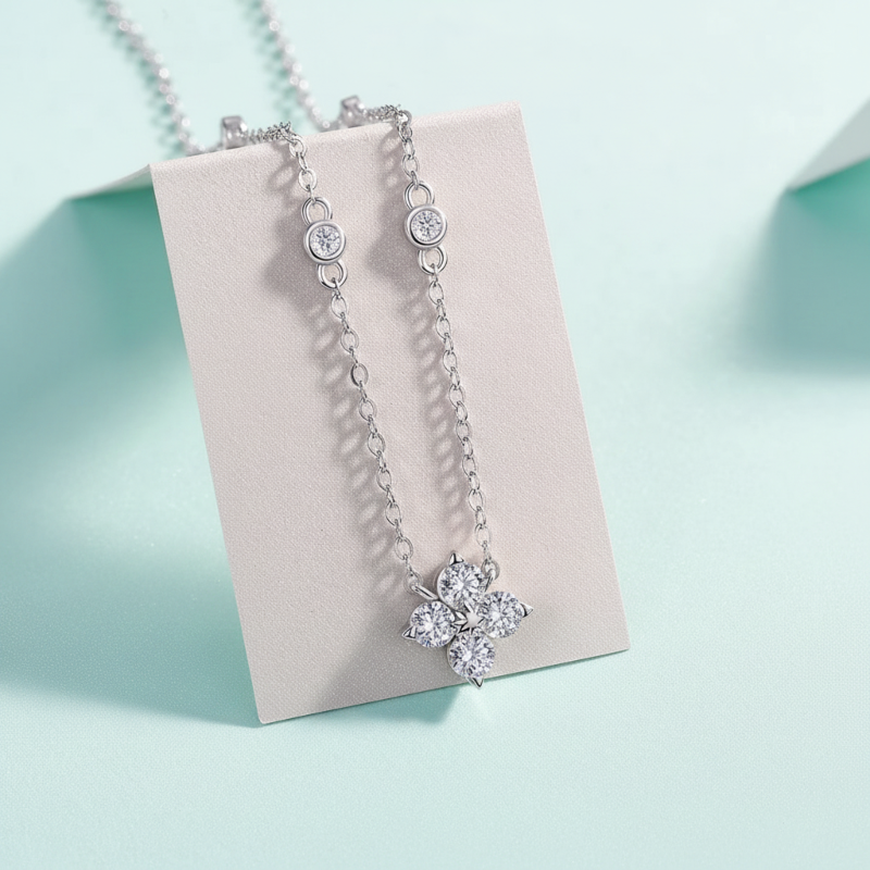 Silver necklace with a floral pendant on a light pink card against a light blue background