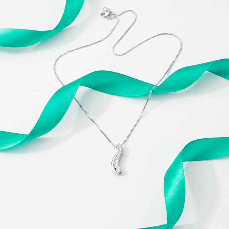 Silver necklace with a pendant on a white background with teal ribbons