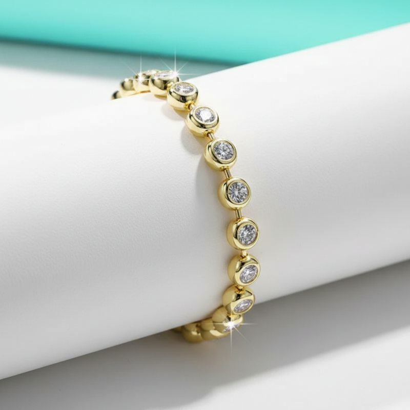 Gold bracelet with clear stones on a white surface with a teal background