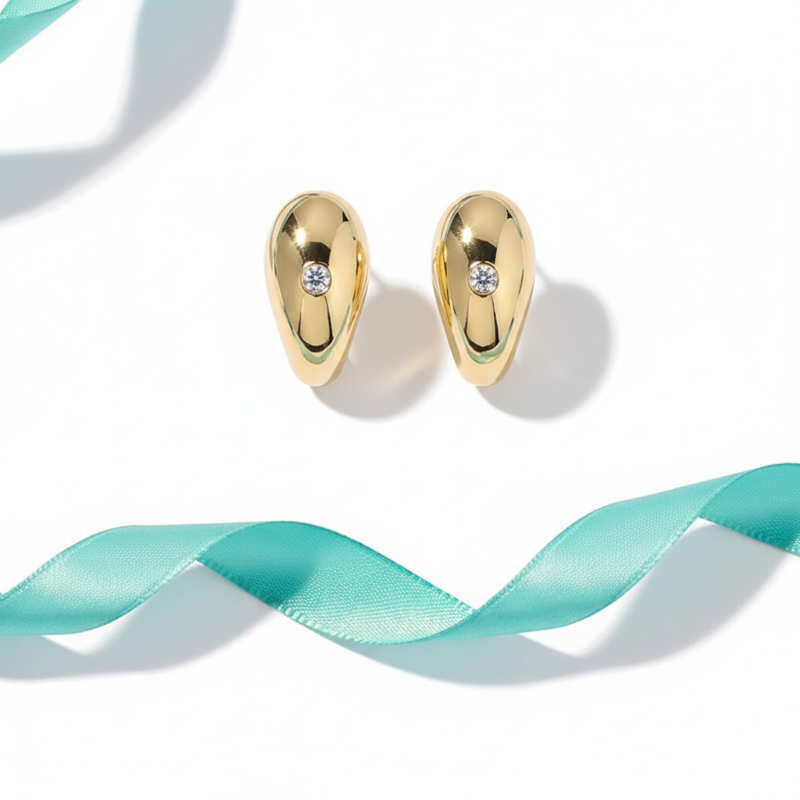 Gold earrings with small diamonds on a white background with a turquoise ribbon.