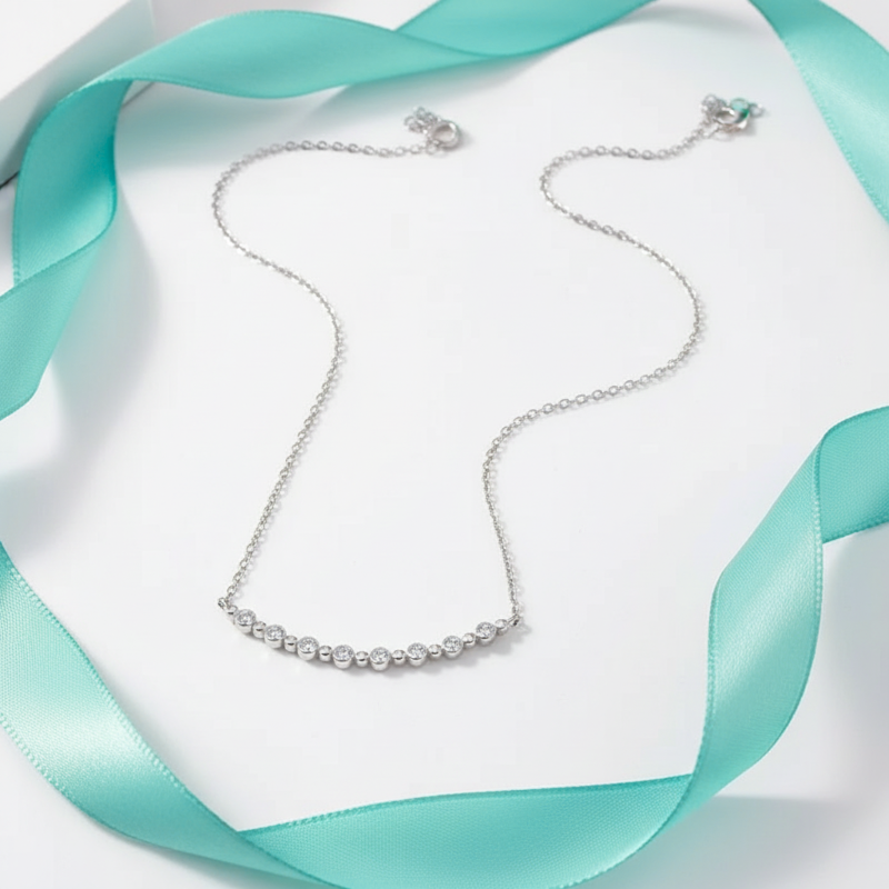Silver necklace on a white and turquoise fabric background
