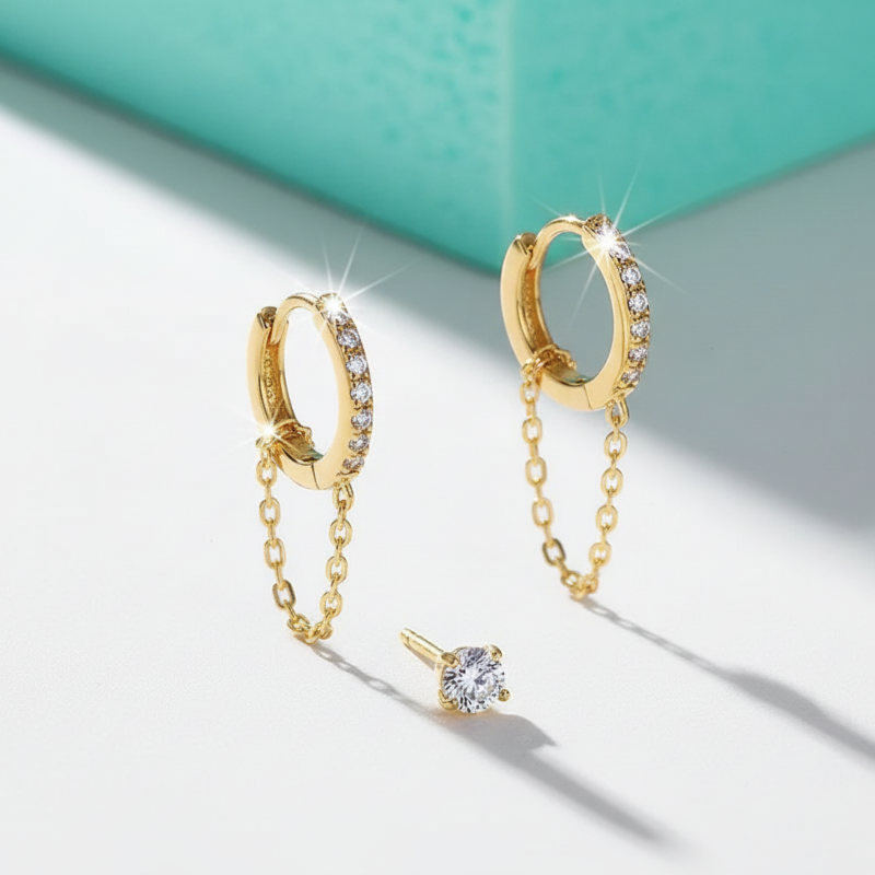 Gold hoop earrings with chain extensions on a light background