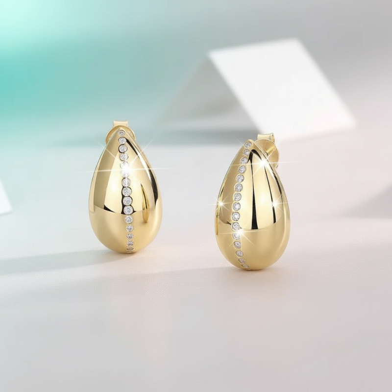 Gold teardrop-shaped earrings with embedded stones on a light background