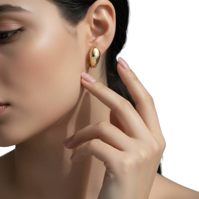 Close-up of a woman wearing a gold earring with a diamond on a white background