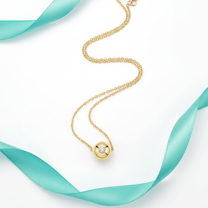 Gold necklace with a diamond pendant on a white background with teal ribbons