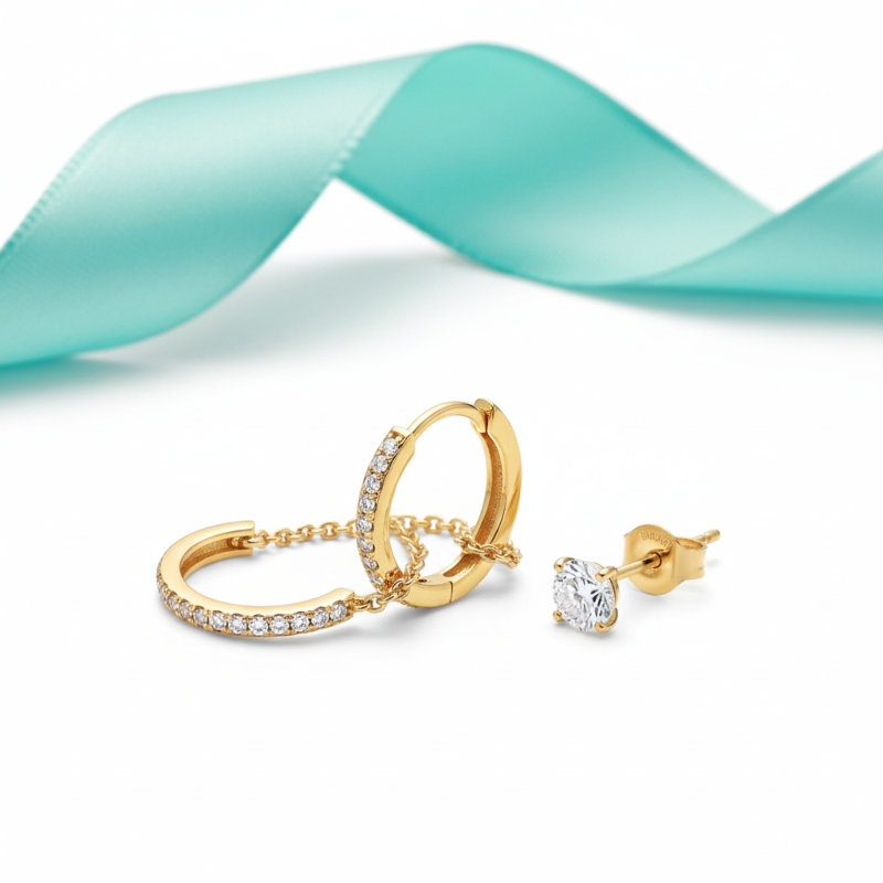 Gold hoop earrings with clear stones on a white background with a turquoise ribbon.