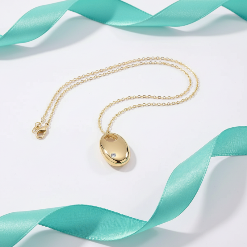Gold necklace with a pendant on a white background with teal ribbons