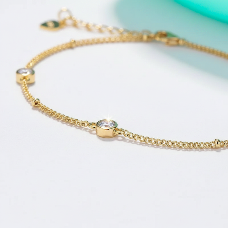 Gold bracelet with small gemstones on a light background