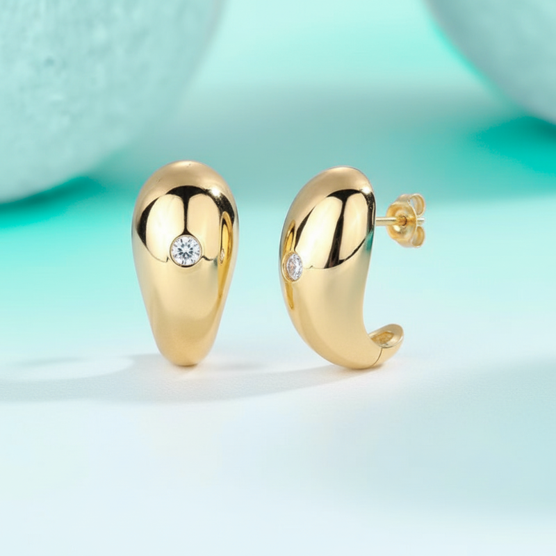 Gold hoop earrings with a central gemstone on a light blue background