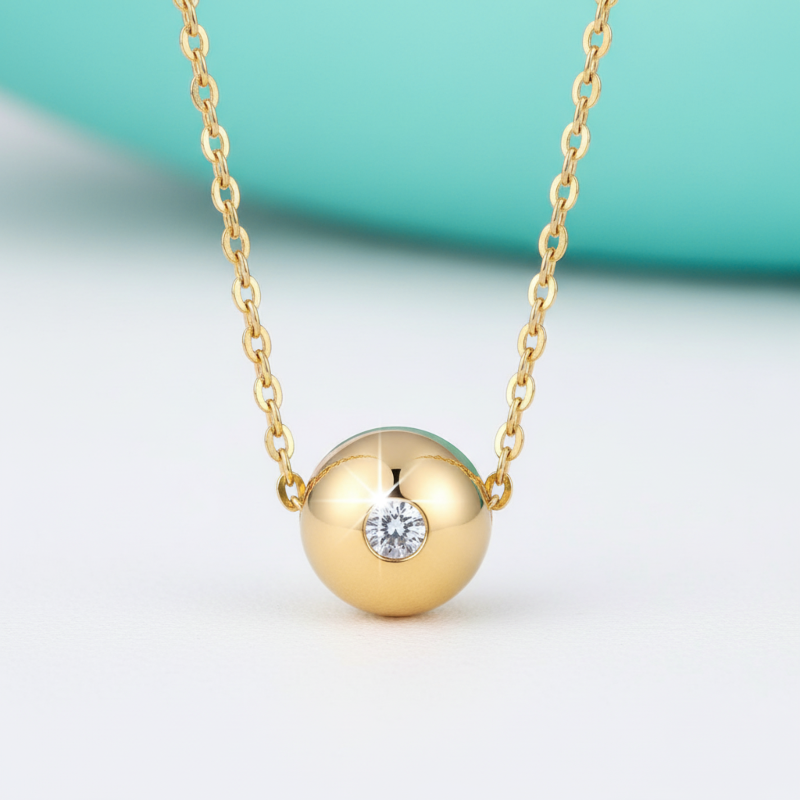 Gold necklace with a round pendant featuring a diamond on a light background