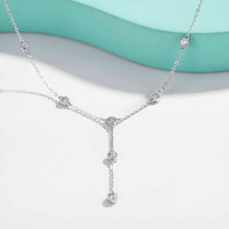 Silver necklace with small pendants on a light blue and white background