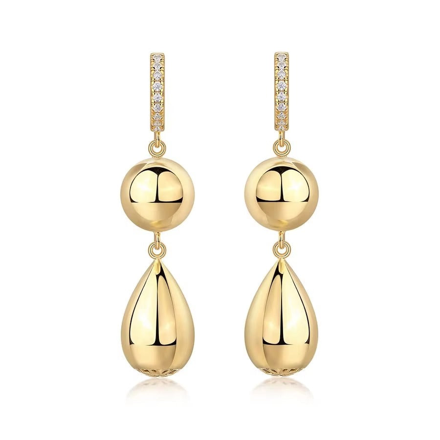 Gold earrings with spherical and teardrop shapes on a white background
