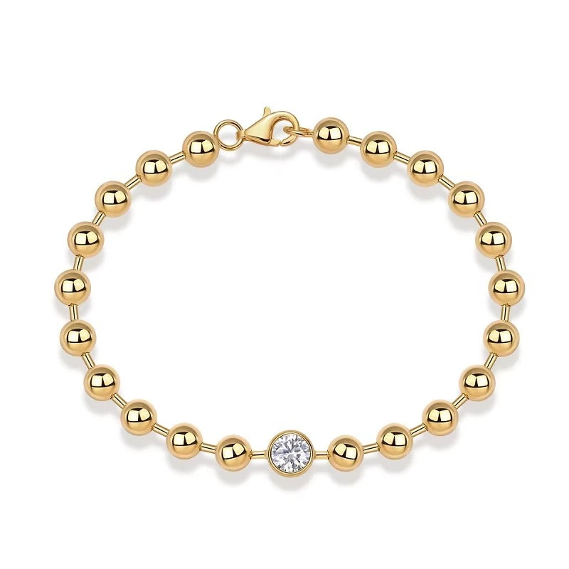 Gold bracelet with a central diamond on a white background