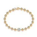 Gold bracelet with a central diamond on a white background